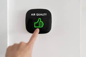 Homeowner touching air quality reader on wall.